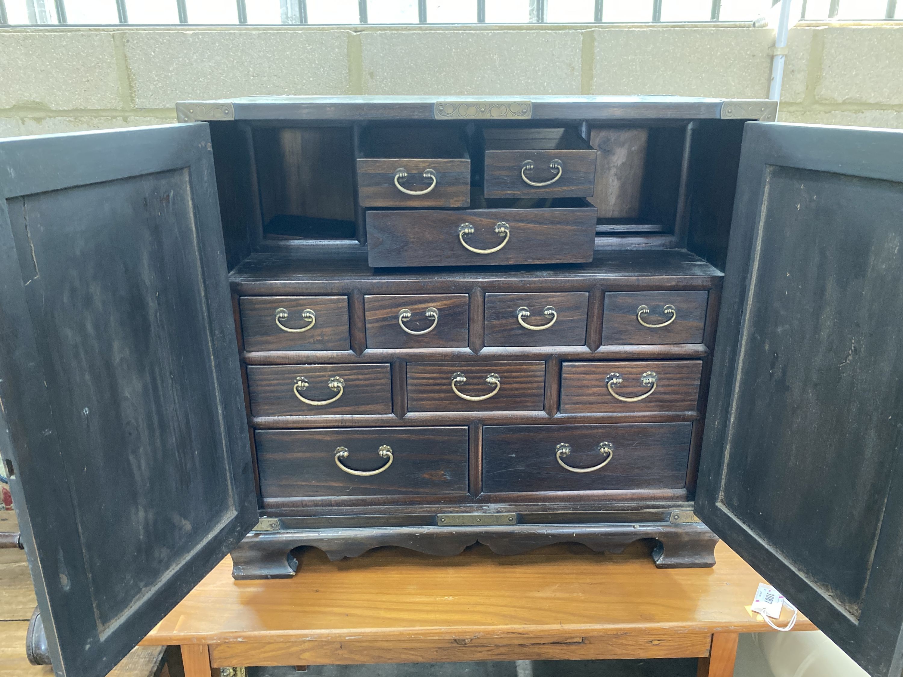 A Korean brass mounted pine table cabinet fitted with an arrangement of drawers, width 70cm, depth 40cm, height 66cm